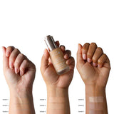 Three hands of different skin tones display four swatches each of 100% Pure 2nd Skin Foundation 35ml (shades 1–8), with the center hand holding a foundation bottle. Swatch labels help show natural complexion matches.