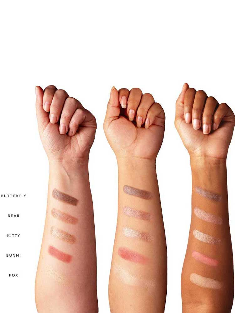 Three forearms in various skin tones display five swatches from the 100% Pure Better Naked Palette 9g—Butterfly, Bear, Kitty, Bunni, and Fox—highlighting these vegan nude eyeshadow shades on different complexions.