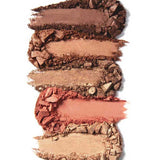 Five horizontal swatches from the 100% Pure Better Naked Palette 9g show warm, neutral vegan eyeshadow shades—ranging from deep brown to gold and peach—stacked on a white background.