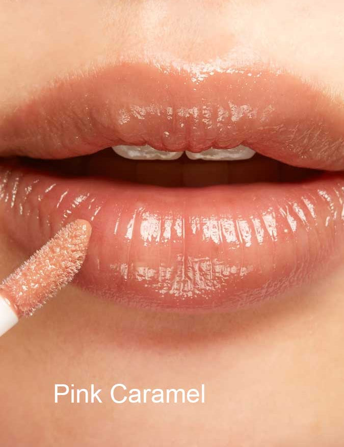 Close-up of lips with 100% Pure Lip Gloss in a light pinkish nude shade, enriched with vitamin E. The shade “Pink Caramel” is labeled in white text at the bottom.
