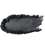 A close-up of a charcoal-black smear of 100% Pure Pressed Eye Shadow 2g by 100% Pure, with rough textured edges, displayed on a white background.