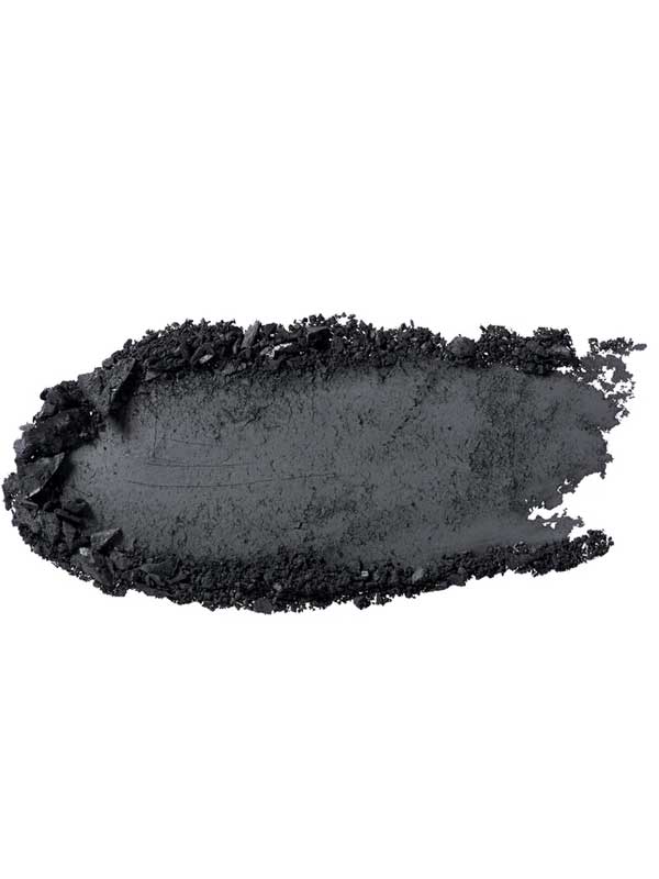 A close-up of a charcoal-black smear of 100% Pure Pressed Eye Shadow 2g by 100% Pure, with rough textured edges, displayed on a white background.