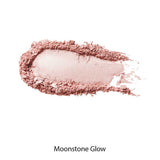 A swatch of 100% Pure Gemmed Luminiser 9g, a shimmery pink pressed powder, is smeared on a white background—perfect for adding a natural glow.