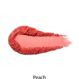 A smear of 100% Pure Rice Powder Pressed Blush 9g in peach on a white background, with "Peach" below, highlights its buildable coverage for a natural-looking flush.