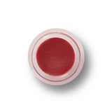 A small, clear round container of 100% Pure Lip & Cheek Tint in the Sugar Plum shade, a reddish-pink hue, viewed from above against a white background.