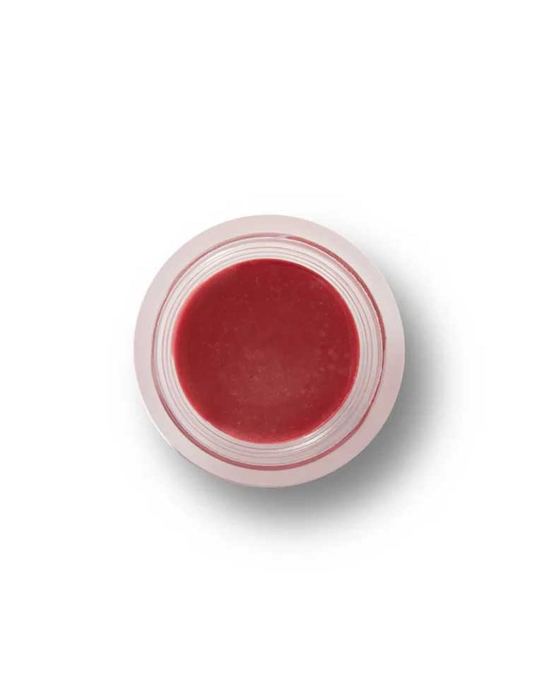 A small, clear round container of 100% Pure Lip & Cheek Tint in the Sugar Plum shade, a reddish-pink hue, viewed from above against a white background.