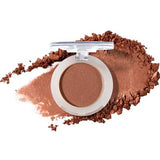 An open compact of 100% Pure Pressed Eye Shadow 2g by 100% Pure with a clear lid, shown on a white background with a swipe and scattered pieces of warm brown, natural mineral shimmer powder.