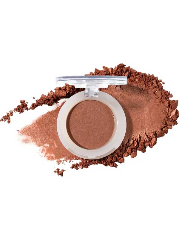 An open compact of 100% Pure Pressed Eye Shadow 2g by 100% Pure with a clear lid, shown on a white background with a swipe and scattered pieces of warm brown, natural mineral shimmer powder.